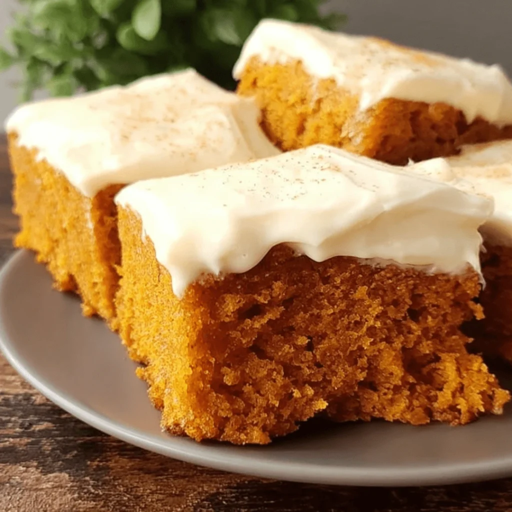 Soft Pumpkin Bars with Cream Cheese Frosting | Easy Fall Dessert Recipe 1 Soft pumpkin bars topped with fluffy cream cheese frosting, cut into squares.