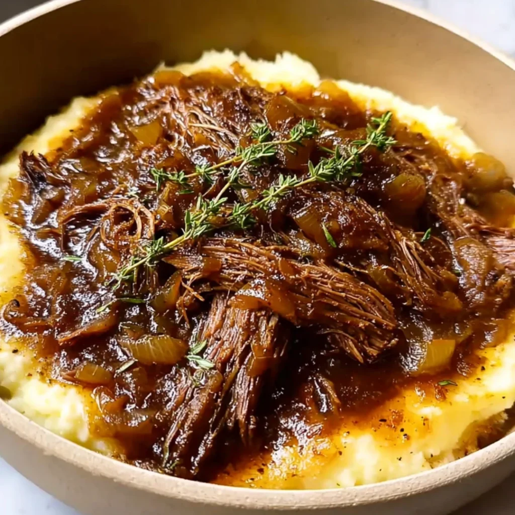 Juicy French onion pot roast in a Dutch oven, topped with caramelized onions and fresh herbs, surrounded by tender potatoes and carrots.